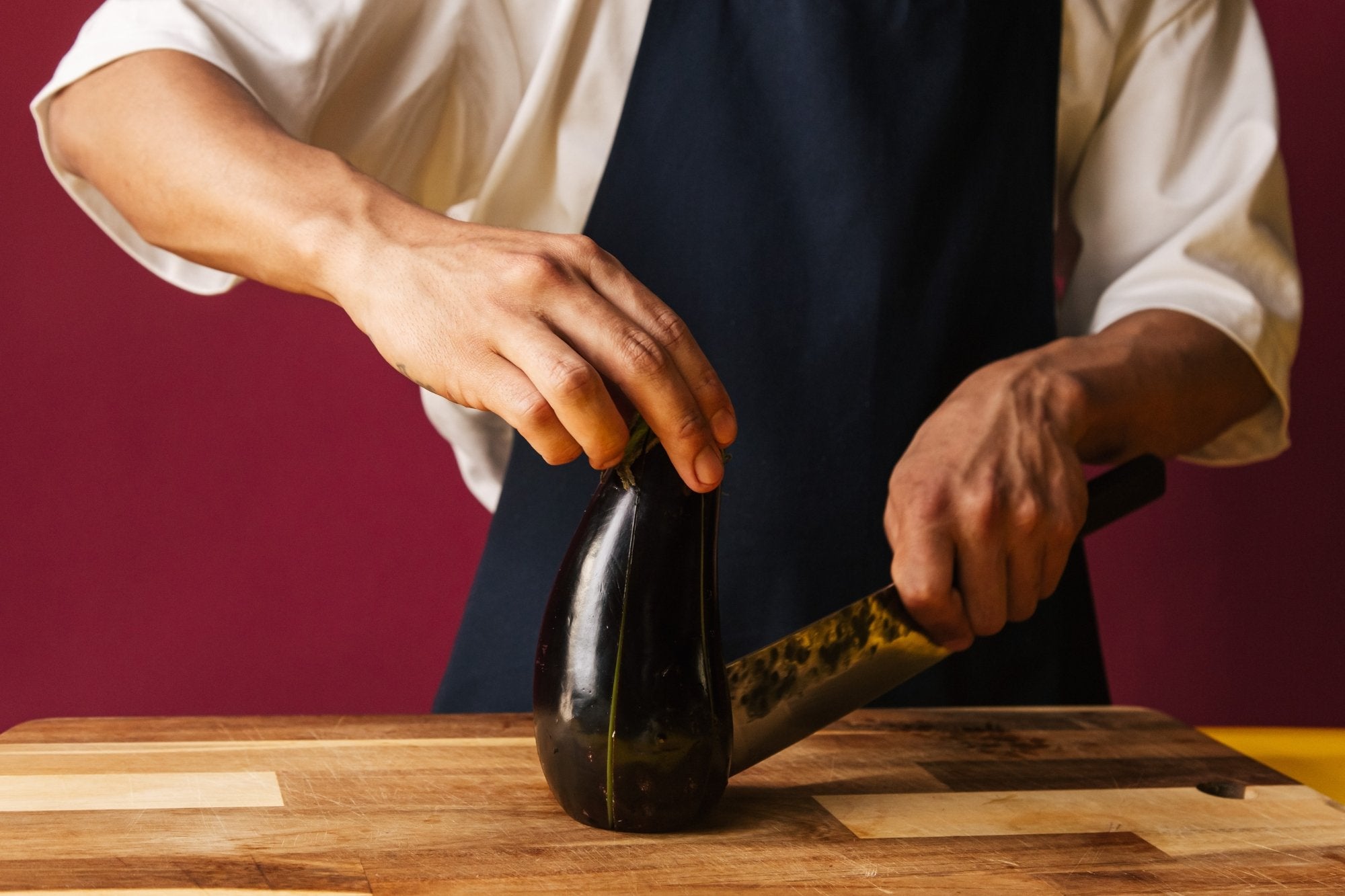 Affettare le melanzane sul bordo di legno con il coltello che